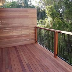 a wooden deck with metal railings and trees in the background