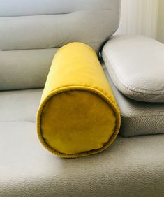 a rolled up pillow sitting on top of a couch next to a white pillow case