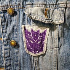 a close up of a person wearing a jean jacket with a purple flower on it