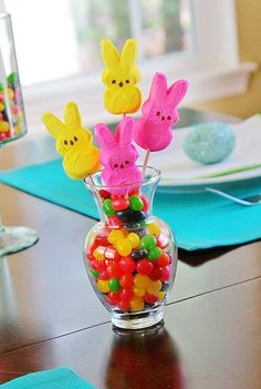 a vase filled with gummy bears and peeps on top of a wooden table