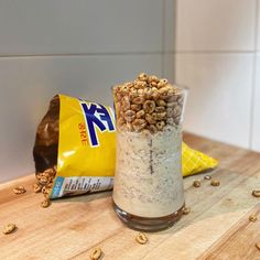 two bags of cereal sitting next to each other on a wooden table with nuts scattered around them