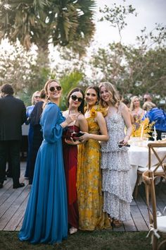 three women standing next to each other at a formal event with drinks in their hands