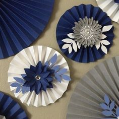 blue and white paper fans are hanging on the wall next to each other with flowers