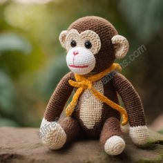 a crocheted monkey with a yellow scarf around its neck sitting on a rock