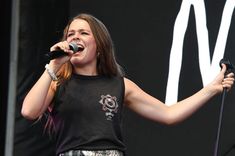 a woman singing into a microphone on stage