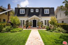 a house that is in the middle of some grass and bushes, with a walkway leading up to it