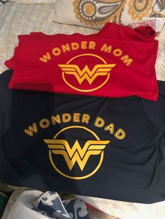 two shirts with wonder mom and wonder dad on them are laying next to each other