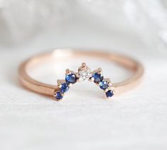 a diamond and blue sapphire ring sitting on top of a white cloth