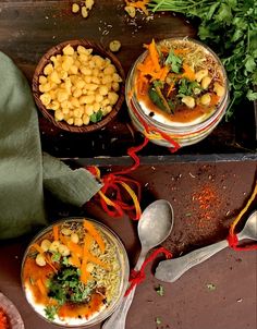 three bowls filled with food sitting on top of a wooden table next to spoons