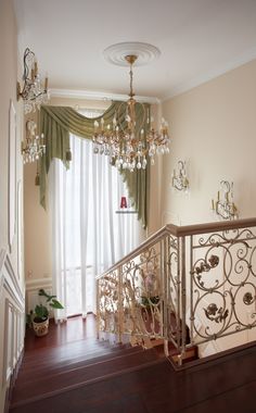 an image of a staircase with chandelier and curtains on the window sill