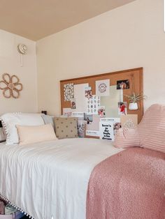 a white bed sitting in a bedroom next to a wooden head board with pictures on it