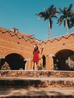 a woman in a red dress is standing on the steps outside an old brick building