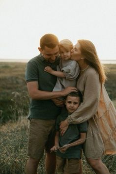 a family is posing for a photo in a field with their two children and one adult