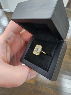 a person is holding up a ring in a box