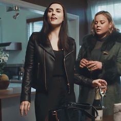 two women standing in a kitchen talking to each other