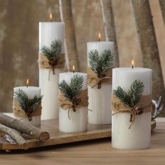 white candles with pine cones and burlocks wrapped in twine on a wooden tray