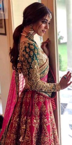 a woman in a red and gold bridal gown standing next to a door with her hand on her hip