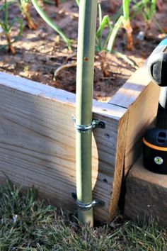 a drill is sitting on top of a piece of wood next to a planter