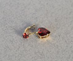 This eye-catching belly ring is sure to capture hearts. This piece features a vibrant heart-cut garnet, renowned for its rich, deep red hue and exceptional clarity. With a discreet screw mechanism, this navel ring hangs from the top of your piercing, creating a weightless, floating effect. - Solid 14k gold - Natural garnets - Internally threaded Total Dimensions: 8 x 20 mm Natural Garnets: 3 mm & 8 x 9 mm We offer three lengths for our floating navel rings: Short: 6 mm Standard: 8 mm Long: 10 mm If you require a custom bar length for your piercing, please feel free to reach out to customerservice@shopnavl.com to arrange a custom order. Small Belly Button Piercing Rings, Floating Belly Piercing, Elegant Heart-shaped Internally Threaded Belly Rings, Floating Navel Piercing Jewelry, Floating Navel Piercing, Floating Navel, Belly Button Piercing Rings, Belly Piercings, Navel Piercing Jewelry