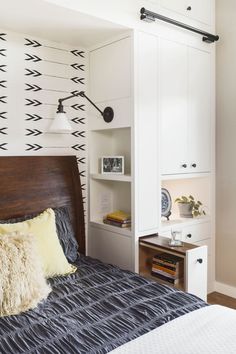 a bed room with a neatly made bed and a book shelf on the wall next to it