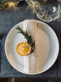 an orange slice on a white plate with a rosemary sprig garnish