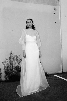 a woman in a long white dress is standing outside