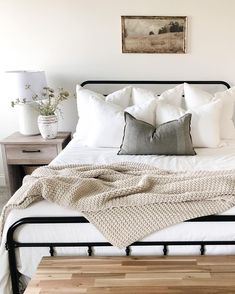 a bed with white pillows and blankets on top of it, next to a night stand