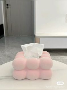 a tissue dispenser sitting on top of a white table in a room