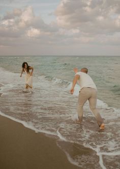 a man and woman playing in the water at the beach