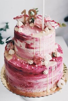 a three tiered cake with pink and white frosting on top, decorated with flowers