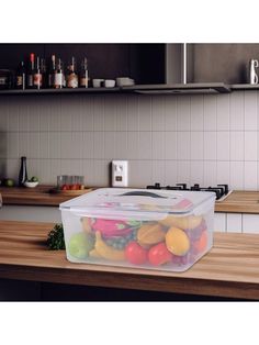 a plastic container filled with fruit sitting on top of a wooden counter in a kitchen