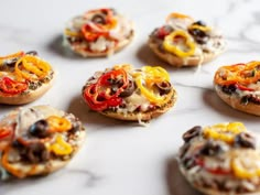 mini pizzas with different toppings are arranged on a marble countertop, ready to be eaten