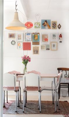 a dining room table with chairs and pictures on the wall