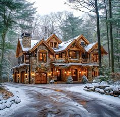 a large stone and wood house in the woods with snow on the ground around it