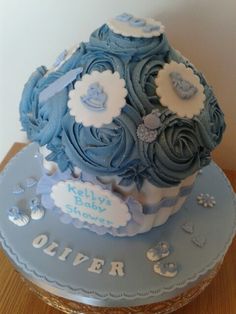 a baby shower cake with blue frosting and flowers on top, sitting on a wooden table