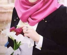 a woman wearing a hijab holding a bouquet of flowers