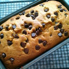 a loaf of chocolate chip banana bread in a green container on a blue tablecloth