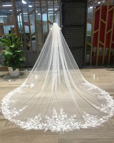 a white wedding veil on the floor in front of a doorway with flowers and greenery