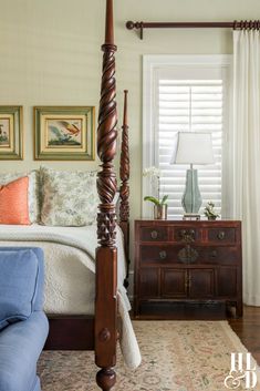 a bedroom with four poster bed and blue couch