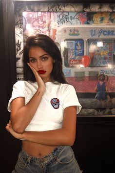 a woman posing in front of a wall with graffiti on it