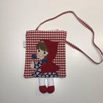 a red and white bag with a doll on it's side hanging from a string