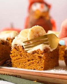 someone is holding a fork over a piece of pumpkin cake with cream cheese frosting