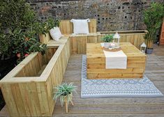 a wooden bench sitting on top of a wooden deck next to plants and potted plants