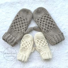 three knitted mittens sitting on top of a white blanket