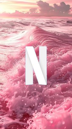 the letter n is surrounded by pink water and waves in front of an ocean sunset