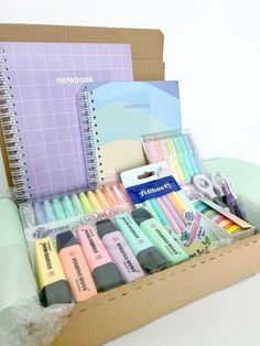 an open box containing pens, markers and notebooks