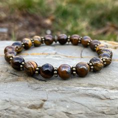 Handmade Genuine Stone Bracelets High-Quality Beaded Bracelet Genuine 8mm Tiger Eye Stone Beads Stretch Bracelet Made With Quality Cord & Antique Bronze Spacers Made With Pure Positive Energy Tiger Eye Properties - Will & Courage - Luck & Success - Prosperity - Grounding & Physical Vitality These Quality Bracelets Will Add A Touch Of Casual Elegance To Your Wardrobe For Any Season Of The Year. All Bracelets Come Carefully Packaged In A Gift Box Ready For Giving. Brown Spiritual Bracelet With Spacer Beads, Spiritual Brown Bracelet With Spacer Beads, Adjustable Polished Beads Bracelets For Meditation, Polished Beads Bracelet For Meditation, Adjustable Bracelets With Spacer And Round Beads, Meditation Beaded Bracelets With Polished Beads, Adjustable Faceted Beads Bracelet For Meditation, Round Polished Beaded Bracelets For Meditation, Brown Spacer Beads Jewelry For Meditation