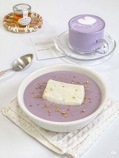 there is a bowl of soup on the table next to a cup and spoons