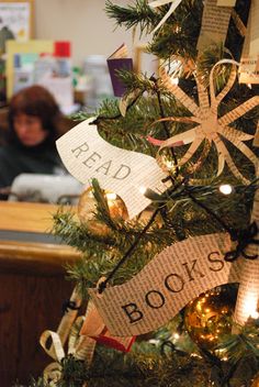 a decorated christmas tree with books on it's sides and people in the background