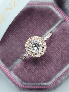 an engagement ring is sitting on top of a purple velvet case with a white and yellow diamond in the center